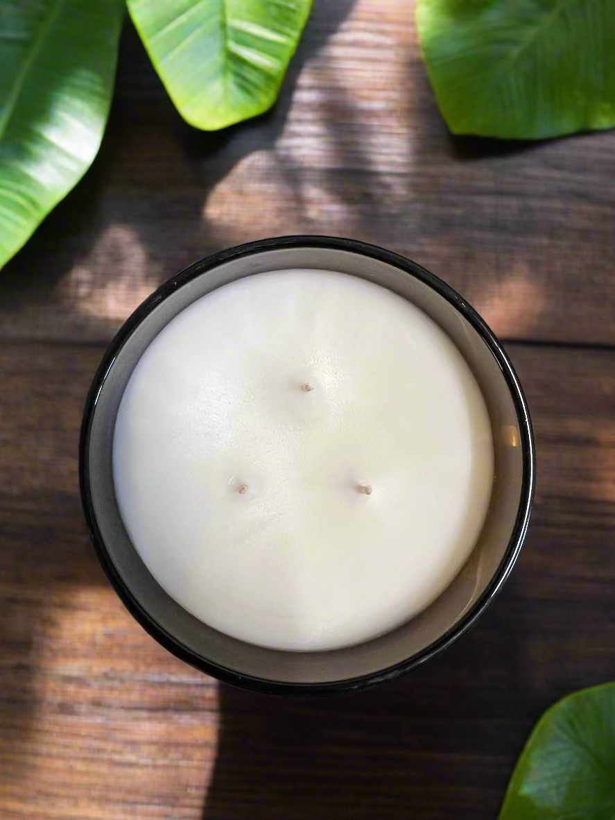 White candle in a black container on a dark surface