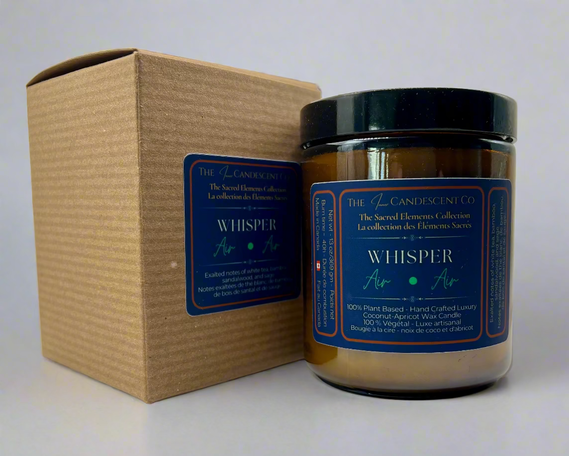 Candle labeled 'Whisper' with a matching cardboard box on a light background