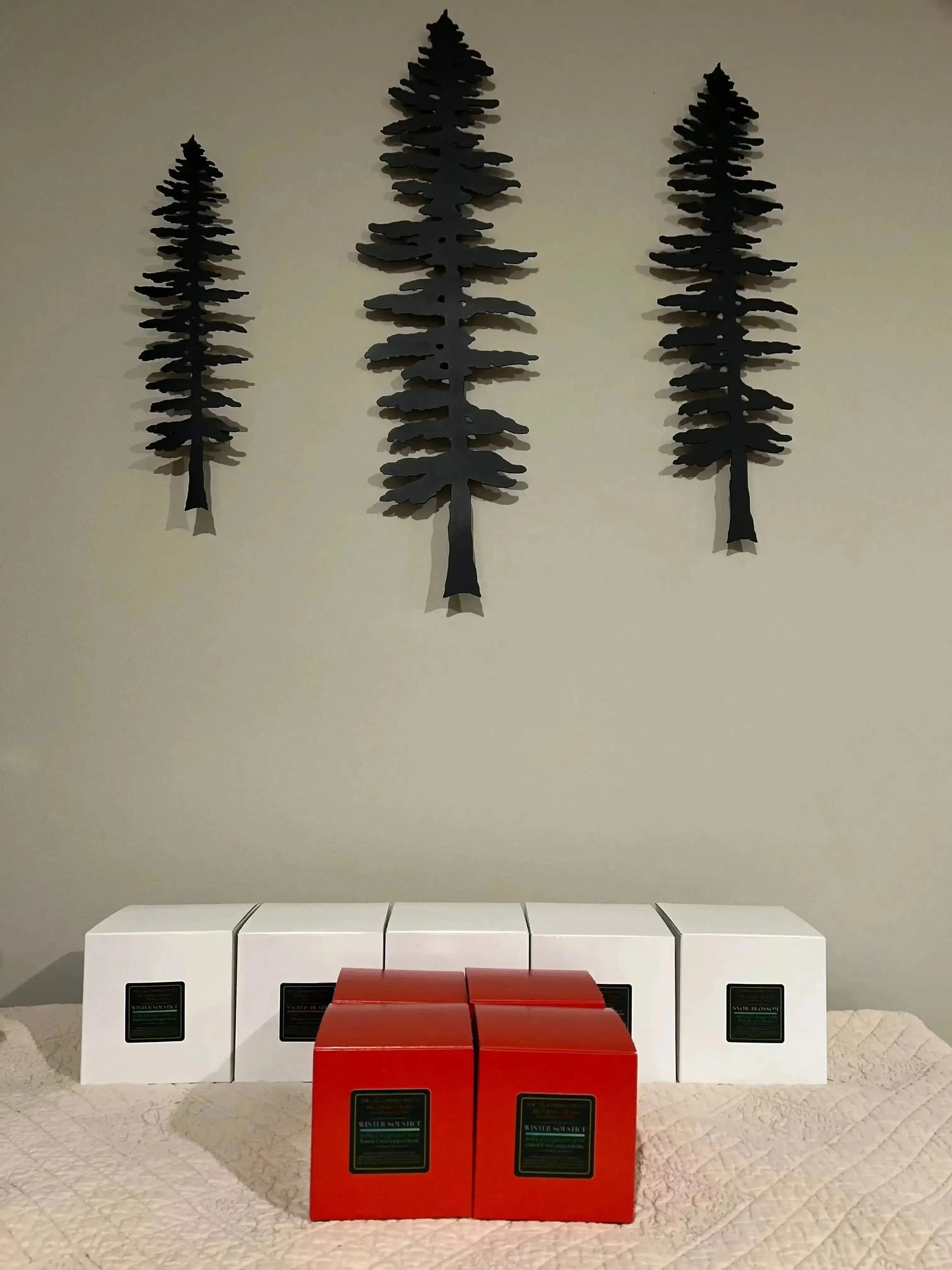 Three black tree-shaped wall decorations on a plain wall with white and red cube-shaped furniture below.