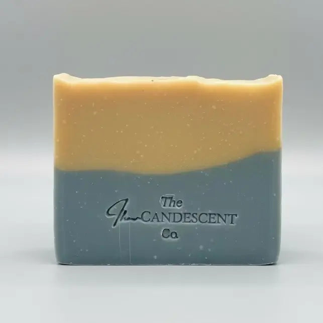 Two-toned soap bar with 'The Candle Shop' branding on a textured surface.