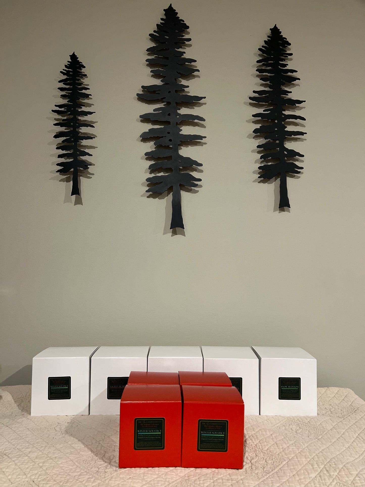 Three black tree-shaped wall decorations on a plain wall with white and red cube-shaped furniture below.